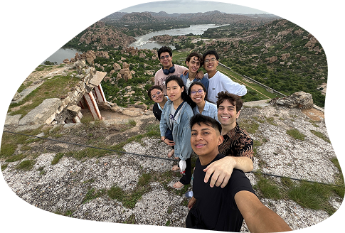 Ada and a group of other young adults on top of a rocky mountain in Hampi, India.